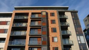 A low-angle shot of a UK block of flats, with blue skies in the background.
