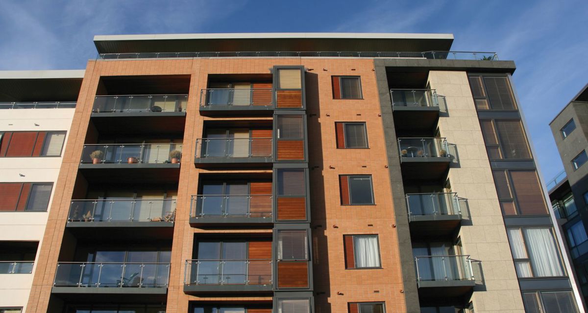 A low-angle shot of a UK block of flats, with blue skies in the background.